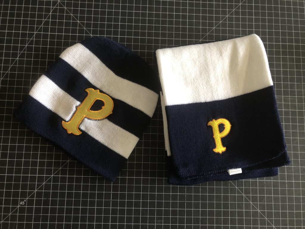 Two folded striped scarves with a yellow 'P' emblem on black and white backgrounds.