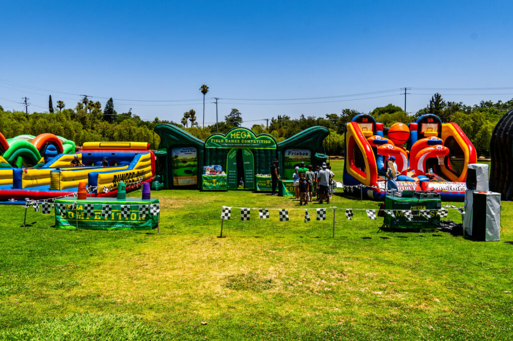 Inflatable obstacle courses on sunny grass field.