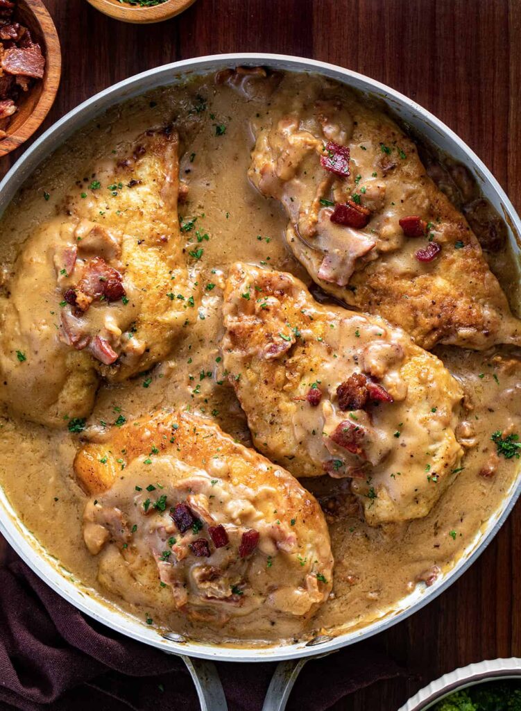 Creamy chicken dish with bacon in skillet.